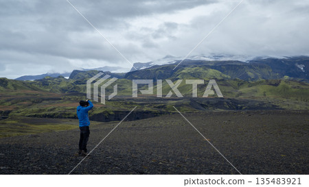 Hiker taking photograph of picturesque Icelandic landscapes and glaciers in front of him, Iceland 135483921