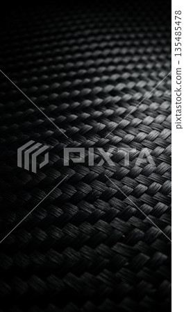 Close-up of a dark, intricate carbon fiber surface featuring a precise diagonal weave and subtle reflective highlights, ideal for a modern background. 135485478