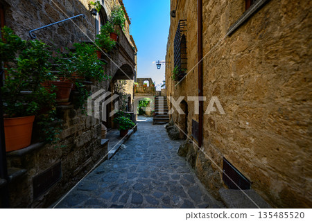 Picturesque medieval-style passageway with stone paving, stairs, and warm sunlight. Authentic old town atmosphere with no people. Picturesque medieval-style passageway with stone paving, stairs, and warm sunlight. Authentic old town atmosphere with no people. 135485520