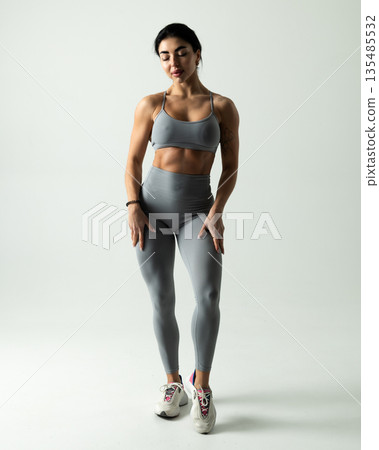 Athletic woman posing in gray sports bra leggings on a white studio background Athletic woman posing in gray sports bra leggings on a white studio background 135485532