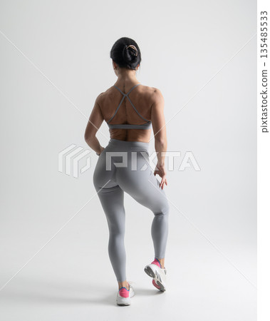 Athletic woman posing in gray sports bra leggings on a white studio background 135485533