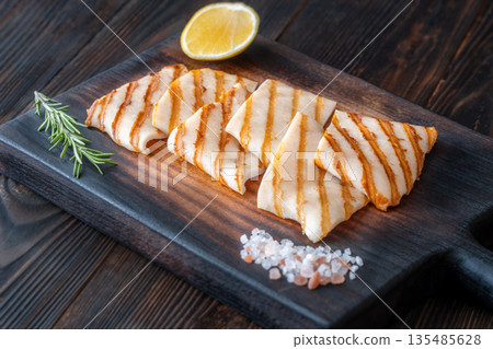 Grilled squid steaks with rosemary and lemon on dark wooden cutting board Grilled squid steaks with rosemary and lemon on dark wooden cutting board 135485628
