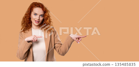 Happy smiling businesswoman presenting and showing something isolated on beige background. Portrait Happy smiling businesswoman presenting and showing something isolated on beige background. Portrait 135485835