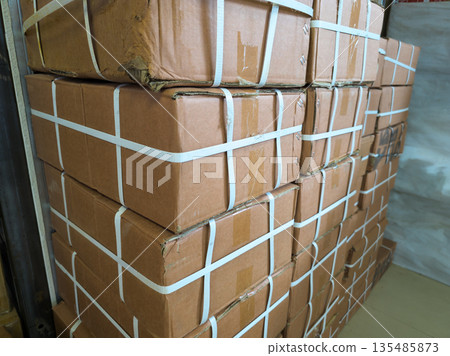 Numerous cardboard boxes stacked indoors in warehouse during day 135485873