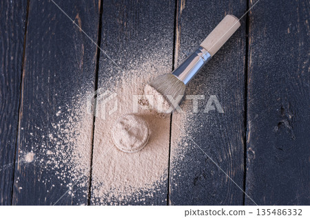 A jar of cosmetics with scattered cosmetics and a make-up brush. Top view. 135486332