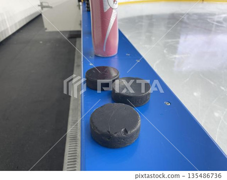 pucks on the side of the ice arena 135486736