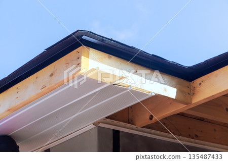 Roof edge construction with wooden beams vinyl siding in home renovation project 135487433