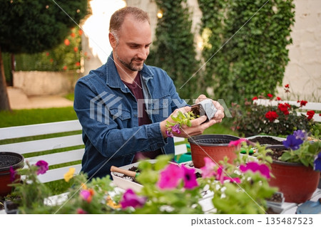 Gardener nurturing seedlings in vibrant outdoor space Gardener nurturing seedlings in vibrant outdoor space 135487523