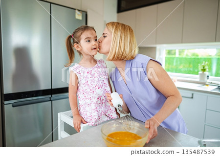 Mother and daughter share joy while baking in the kitchen 135487539