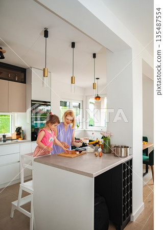 Mother and daughter cooking together in a bright kitchen 135487554