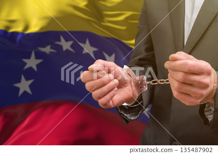 Man in handcuffs in front of the national flag of Venezuela Man in handcuffs in front of the national flag of Venezuela 135487902