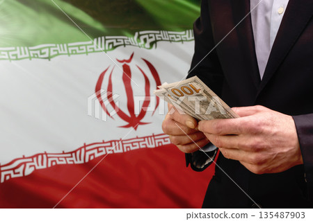 Man holding US dollars in front of the Iranian flag Man holding US dollars in front of the Iranian flag 135487903