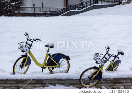 Two bicycles covered with snow while snowing in winter Two bicycles covered with snow while snowing in winter 135488530