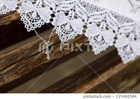 Silver Cross Necklace on Wooden Church Bench with Lace Cloth Silver Cross Necklace on Wooden Church Bench with Lace Cloth 135488564