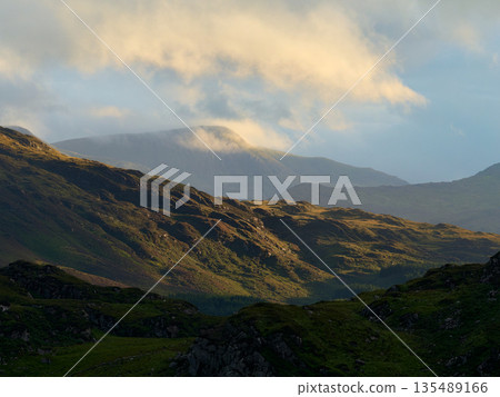 A scenic mountain landscape bathed in golden sunlight. 135489166