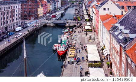 Sunset over Nyhavn (old port)- landmark in Copenhagen - with cafe and old (historic) ships, sailboats . Sunset over Nyhavn (old port)- landmark in Copenhagen - with cafe and old (historic) ships, sailboats . 135489503