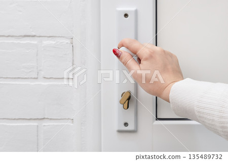 A woman's hand opens a white door A woman's hand opens a white door 135489732