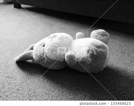 Plush Bunny Toy Lying on Floor Black White. Cute stuffed bunny rabbit plush toy fallen on carpet floor, black and white moody shot. Childhood nostalgia concept. 135489823