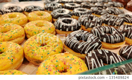 Colorful Sprinkled Donuts Assortment. Fresh assorted donuts with colorful sprinkles, chocolate glaze and white icing on display. Sweet bakery treats, dessert and food indulgence concept. Colorful Sprinkled Donuts Assortment. Fresh assorted donuts with colorful sprinkles, chocolate glaze and white icing on display. Sweet bakery treats, dessert and food indulgence concept. 135489824