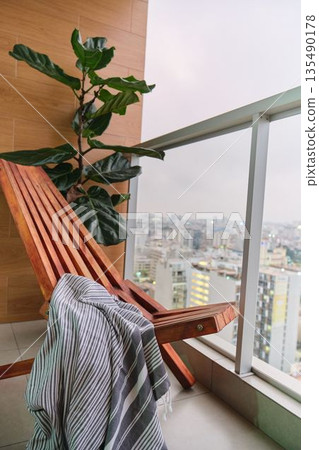 Urban high-rise balcony with lounge chair and city view 135490178