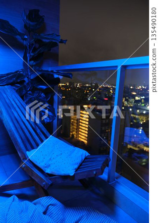 Balcony and lounge chair with blue light and cityscape view 135490180