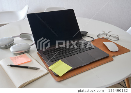 Home office workspace with laptop, headphones, and productivity items 135490182