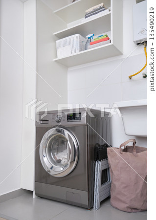 Modern laundry room interior with washing machine and storage shelves Modern laundry room interior with washing machine and storage shelves 135490219