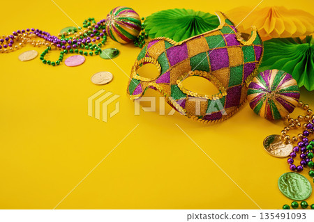 Mardi gras mask beads on yellow background Mardi gras mask beads on yellow background 135491093