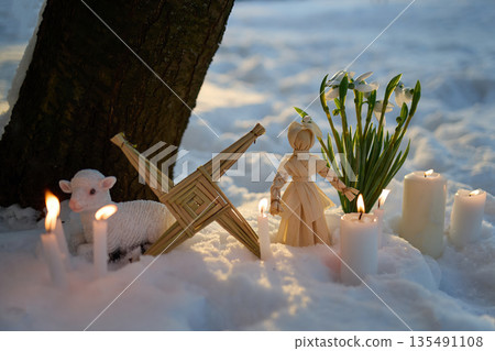 Imbolc brigid's cross with doll, lamb, snowdrops and candles in snow Imbolc brigid's cross with doll, lamb, snowdrops and candles in snow 135491108