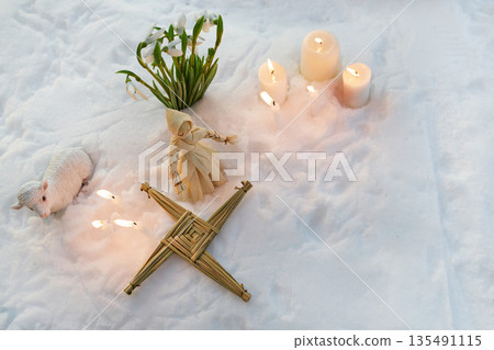 Imbolc celebration with brigid's cross, snowdrops, and candles in snow Imbolc celebration with brigid's cross, snowdrops, and candles in snow 135491115