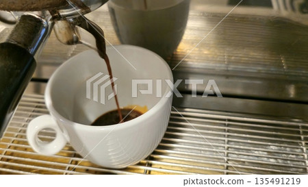 Freshly Brewed Espresso Pouring into White Cup 135491219