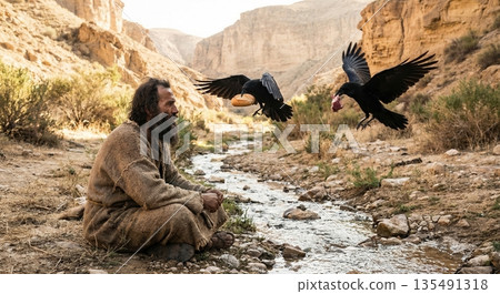 Elijah the Prophet sits by a flowing stream in a desert landscape. Two ravens fly nearby delivering food to him. This scene shows faith and survival in harsh conditions. 135491318