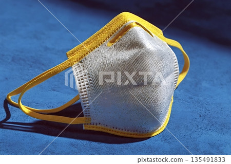 Protective face mask resting on blue surface Protective face mask resting on blue surface 135491833