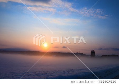 A sub-zero dawn and morning mist in a landscape with a silo A sub-zero dawn and morning mist in a landscape with a silo 135492539
