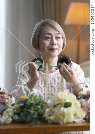 一位老婦人在客廳插花，這是她的愛好。自然光 135492814
