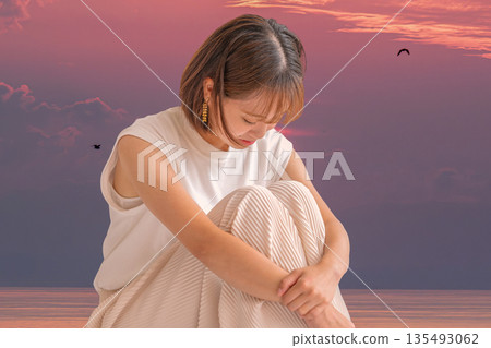 The sea at dusk and a depressed woman The sea at dusk and a depressed woman 135493062