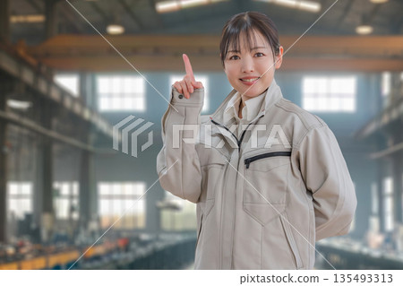 Factory and woman in work clothes pointing Factory and woman in work clothes pointing 135493313