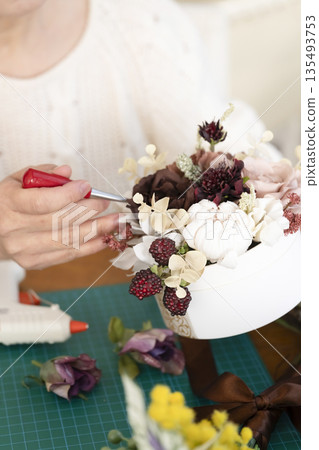 一位老婦人在客廳擺弄花材,這是她的愛好。 一位老婦人在客廳擺弄花材,這是她的愛好。 135493753