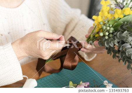 The hands of a senior woman arranging flowers as a hobby in the living room The hands of a senior woman arranging flowers as a hobby in the living room 135493763