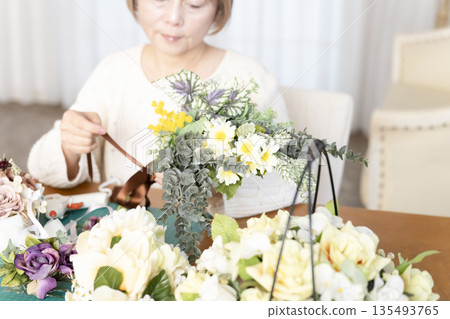一位老婦人在客廳擺弄花材,這是她的愛好。 一位老婦人在客廳擺弄花材,這是她的愛好。 135493765