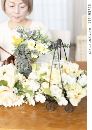 一位老婦人在客廳擺弄花材，這是她的愛好。 135493766