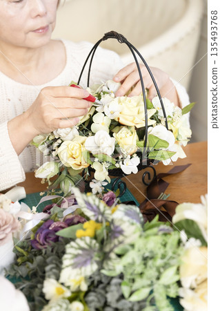 一位老婦人在客廳擺弄花材，這是她的愛好。 135493768