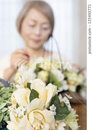 The hands of a senior woman arranging flowers as a hobby in the living room 135493771