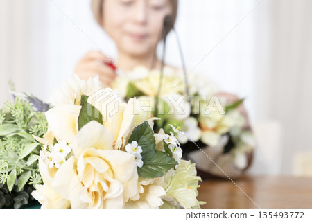 The hands of a senior woman arranging flowers as a hobby in the living room 135493772