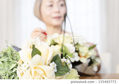 The hands of a senior woman arranging flowers as a hobby in the living room The hands of a senior woman arranging flowers as a hobby in the living room 135493773