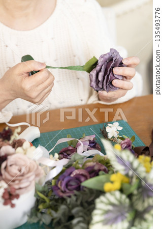 The hands of a senior woman arranging flowers as a hobby in the living room 135493776