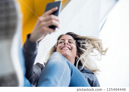 Smiling young woman taking a selfie with smartphone from a low angle perspective 135494446