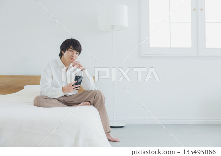 Men watching smartphones in bed Men watching smartphones in bed 135495066