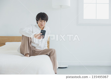 Men watching smartphones in bed Men watching smartphones in bed 135495067