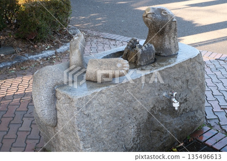 A water faucet made of stone that resembles an otter's entire body 135496613